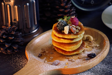 Pancake with berries and nut and cereal on wood plate.