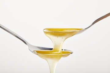 close up view of spoons with honey on white background