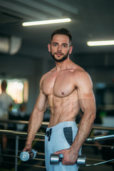 Fototapeta na wymiar A young athlete trains in the gym. Trians biceps muscules