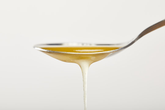 Close Up View Of Spoon With Natural Honey On Grey Backdrop