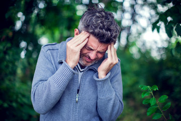Portrait of a sick man having a migraine outdoor. Healthcare, medicine and people concept