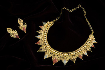 Modern golden necklace on a dark pattern