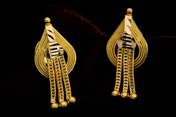Golden earrings on a dark pattern