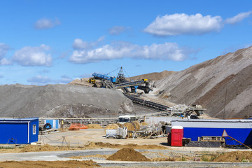 dumps of mined rock with belt conveyors, stackers and working bulldozer, general view - Powered by Adobe