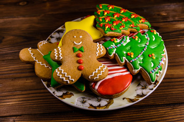 Plate with different christmas gingerbread cookies on wooden table