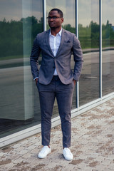 fashionable and successful African businessman American handsome man in a stylish luxury suit posing on the street business center office skyscraper background fashion model