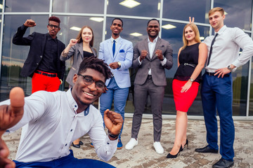 handsome smiling businessman african american man in a stylish suit and european partner successful multiracial business men and female perspon team taking selfie together on camera