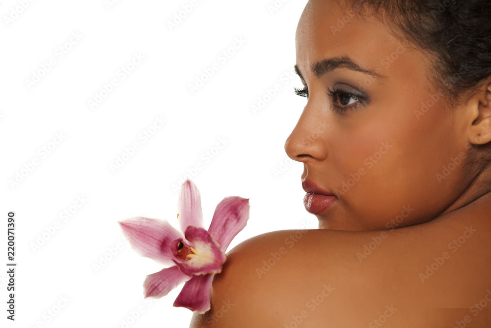 Wall mural profile of young beautiful dark-skinned woman with orchid on a white background