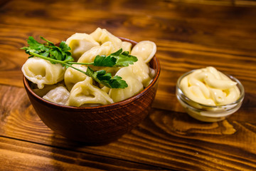 Fresh dumplings in ceramic bowl on wooden table