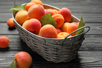 Basket with ripe sweet apricots on wooden background