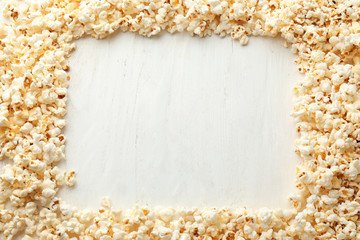 Frame made of delicious popcorn on white wooden background