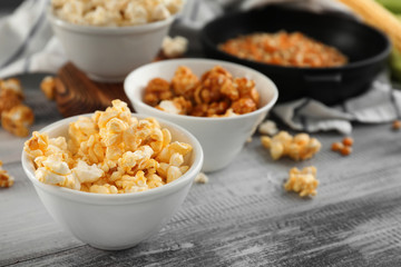 Bowls with delicious popcorn on wooden background