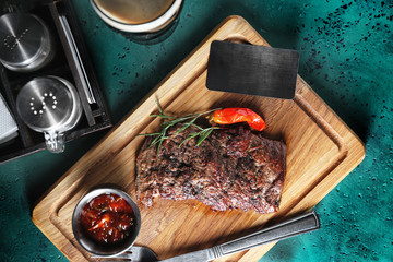 Delicious grilled steak with sauce and blank card on wooden board
