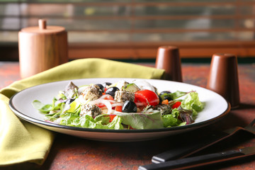 Plate with delicious fresh salad on color table