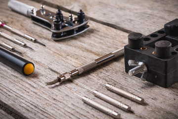 Set of watchmaker tools isolated on a rough wooden board