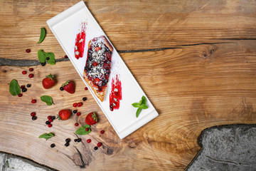 Plate with delicious berry cake and jam on wooden table