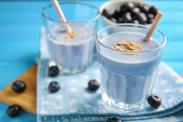 Glasses with tasty blueberry smoothie on color wooden table