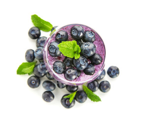 Glass of tasty blueberry smoothie on white background, top view