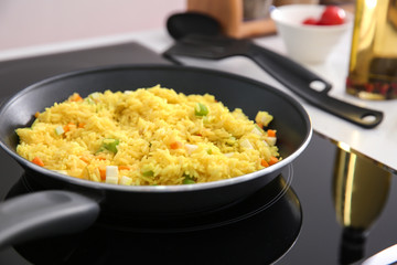 Frying pan with delicious rice on electric cooker