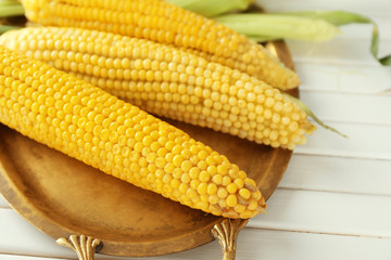 Tray with tasty corn cobs on wooden background, closeup