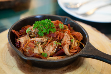 Sizzling hot and spicy Spaghetti alla salsiccia with sausage and bacon in a black cast iron pan on a wooden board. Simple classic Italian meal. Perfect for lunch. Natural light. Selective focus.