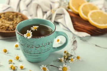 Obraz na płótnie Canvas Cup of delicious camomile tea on light table, closeup
