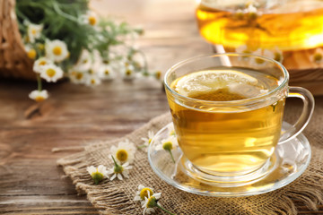 Cup of delicious camomile tea on wooden table