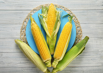 Board with fresh corn cobs on wooden table