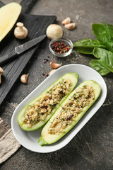 Plate with quinoa stuffed zucchini boats and spices on grunge table