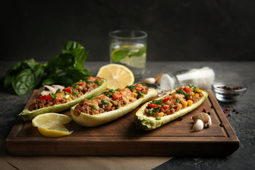 Board with meat stuffed zucchini boats on grunge table