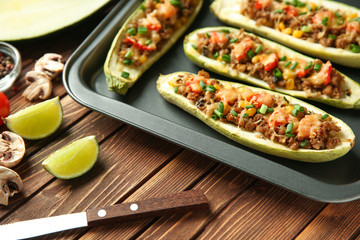 Tray with meat stuffed zucchini boats on wooden table, closeup