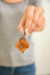 Woman holding key with trinket in shape of house, closeup