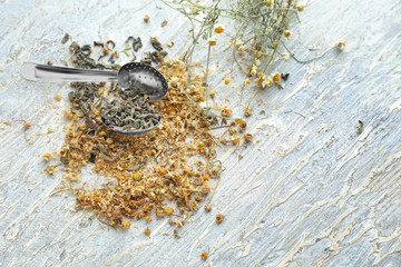 Tea strainer with dried chamomile flowers on wooden table