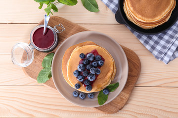 Composition with tasty pancakes and blueberries on wooden table