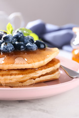Plate with tasty pancakes and blueberries on table, closeup