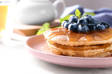 Plate with tasty pancakes and blueberries on white table, closeup