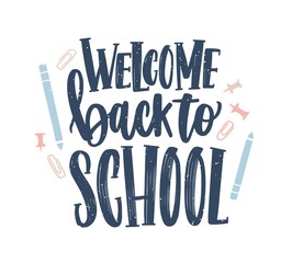 Welcome Back to School lettering handwritten with elegant calligraphic font and decorated by paper clips, push pins and pencils scattered around. Colorful vector illustration for 1st of September.