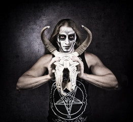 Portrait of man in goth style clothes with scull in his hand.