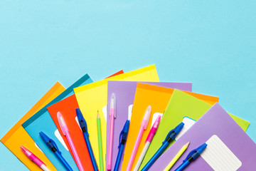 Flat lay composition with various notebooks, pens and pencils on a colored blue background. School supplies, the idea of going back to school