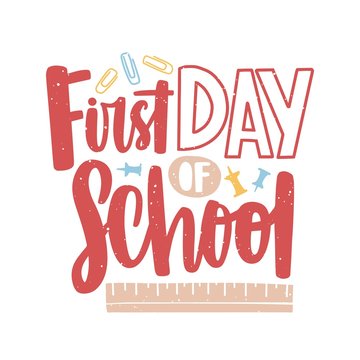 First Day of School lettering written with calligraphic font and decorated by paper clips, push pins and ruler scattered around. Decorative text isolated on white background. Vector illustration.