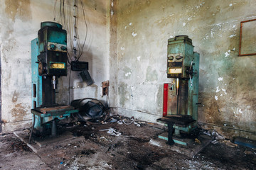 Fototapeta na wymiar Old rusty industrial drilling machine tools in abandoned factory workshop looks like robots