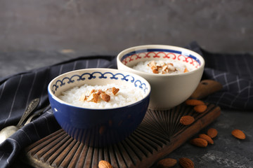 Bowls with delicious rice pudding and nuts on board