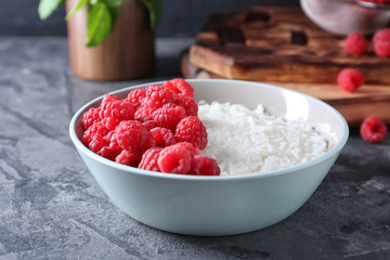 Bowl with delicious rice pudding and raspberry on table