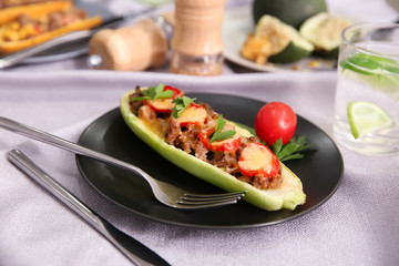 Plate with meat stuffed zucchini boat on table