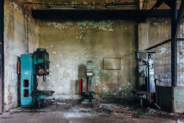 Fototapeta na wymiar Old rusty industrial drilling machine tools in abandoned factory workshop looks like robots