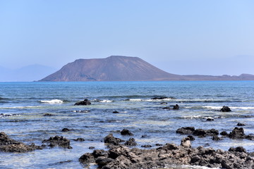 Beach of Corralejo Bay at morning against blue sky with Lobos Island and Lanzarote on background