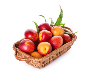 Basket with fresh peaches on white background
