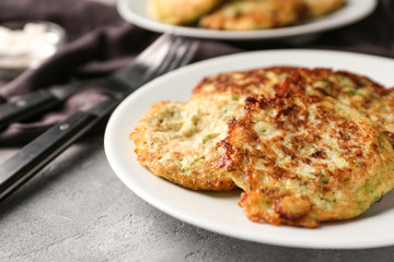 Plate with zucchini pancakes on table, closeup
