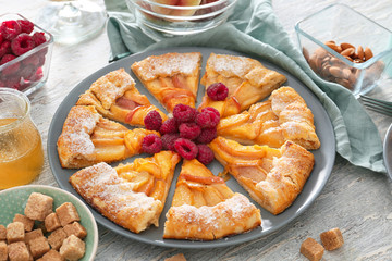 Plate with delicious peach galette and products on light table
