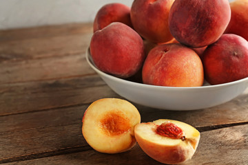 Fototapeta na wymiar Bowl with fresh peaches on wooden table, closeup